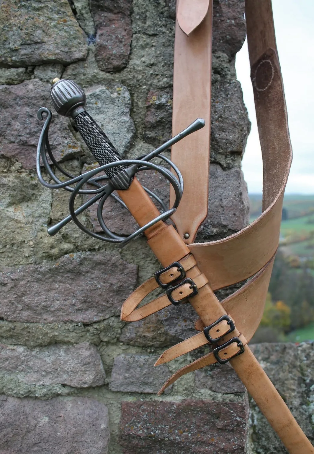 Rapier mit Lederriemen vor historischem Mauerwerk